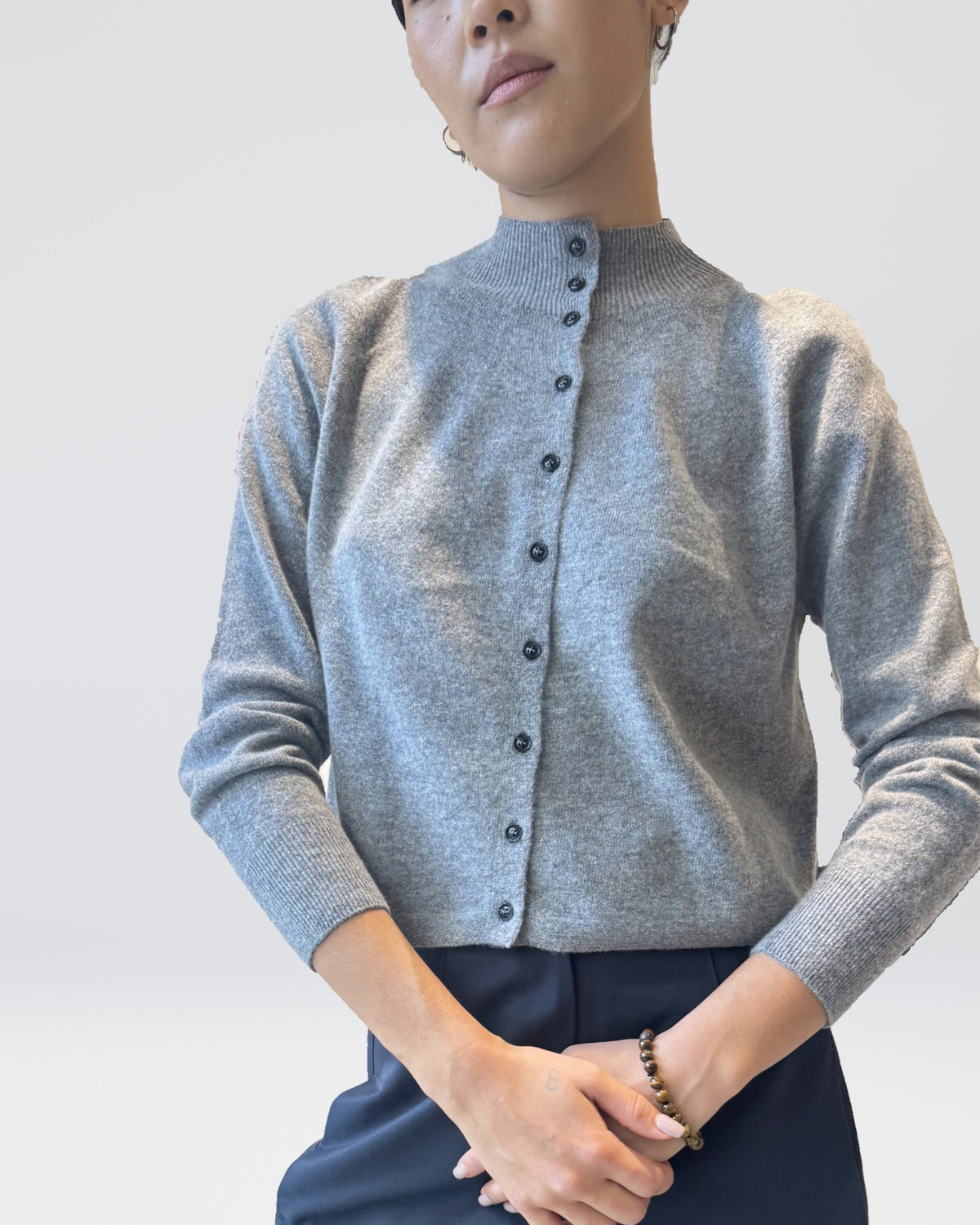 Anujin wearing High Neck Cardigan, Melange Grey, with Twist Pants Berge — knit and button detail.