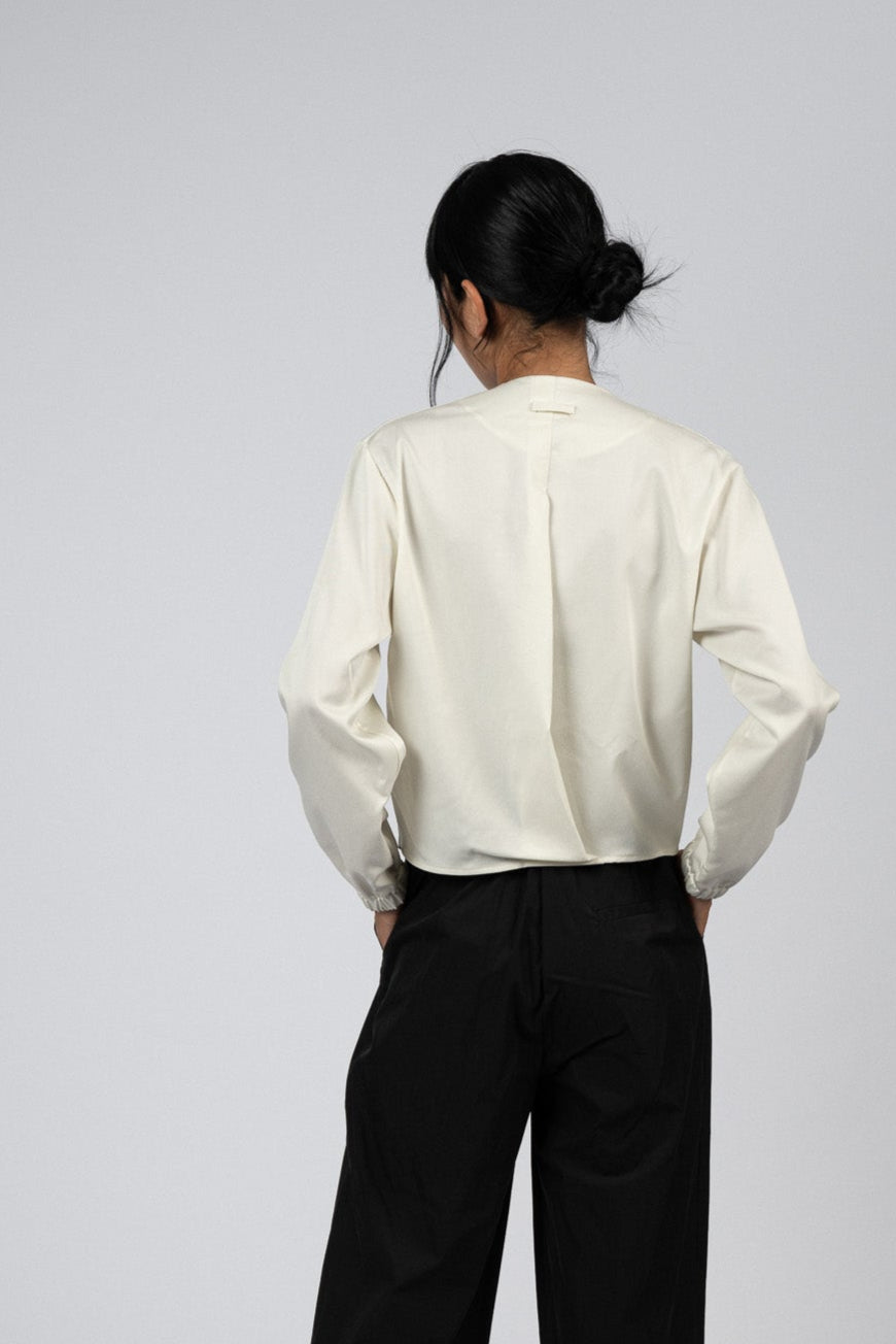 Person wearing a white shirt and black pants on a plain background