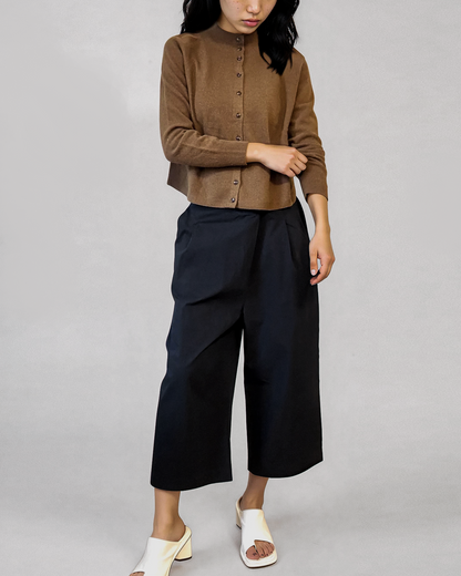 Person wearing a brown shirt and black pants on a plain background