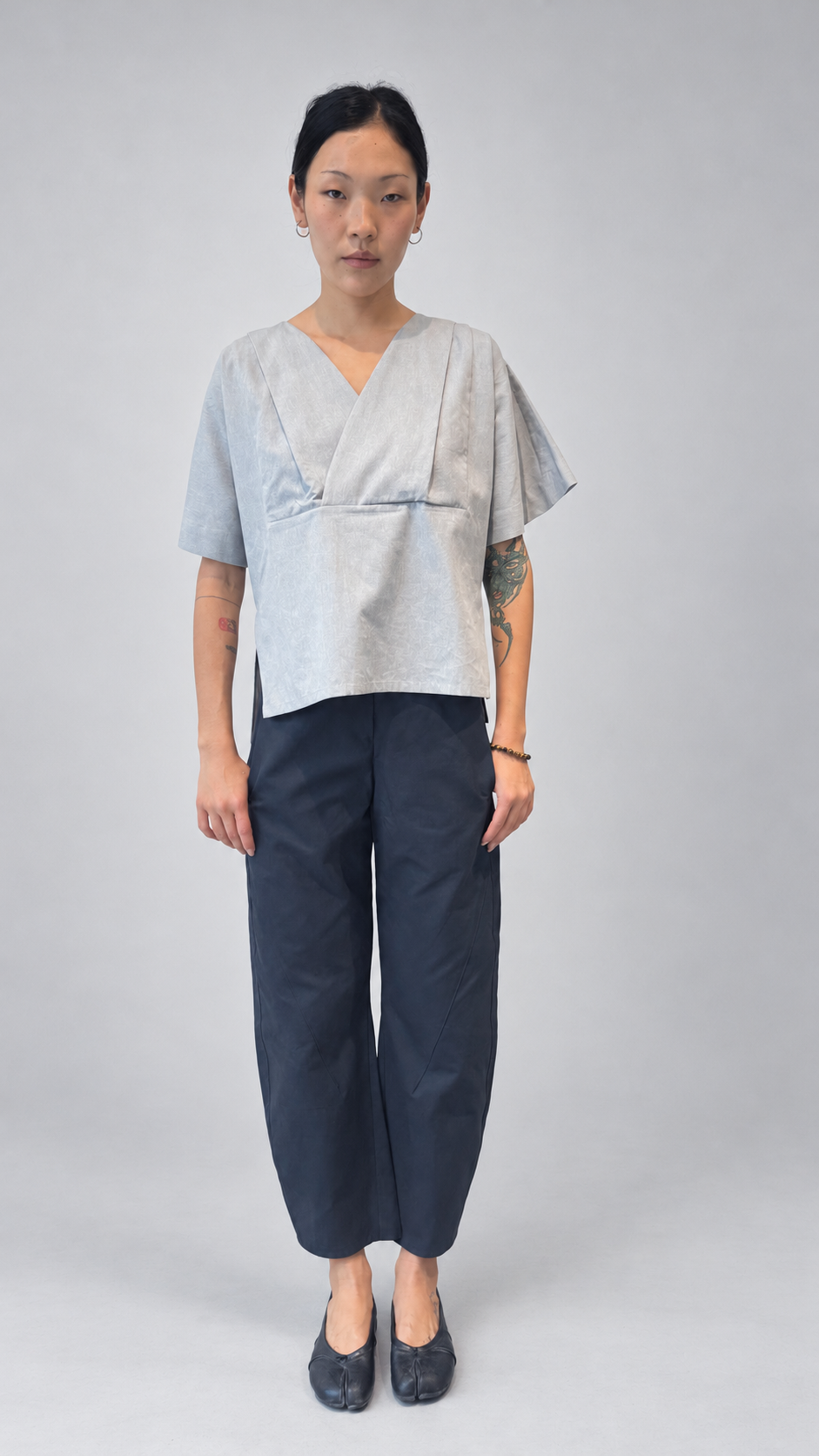 Lotus Shirt, Temple Grey — front model view. Anujin wearing lotus shirt temple grey, twist pants berge.