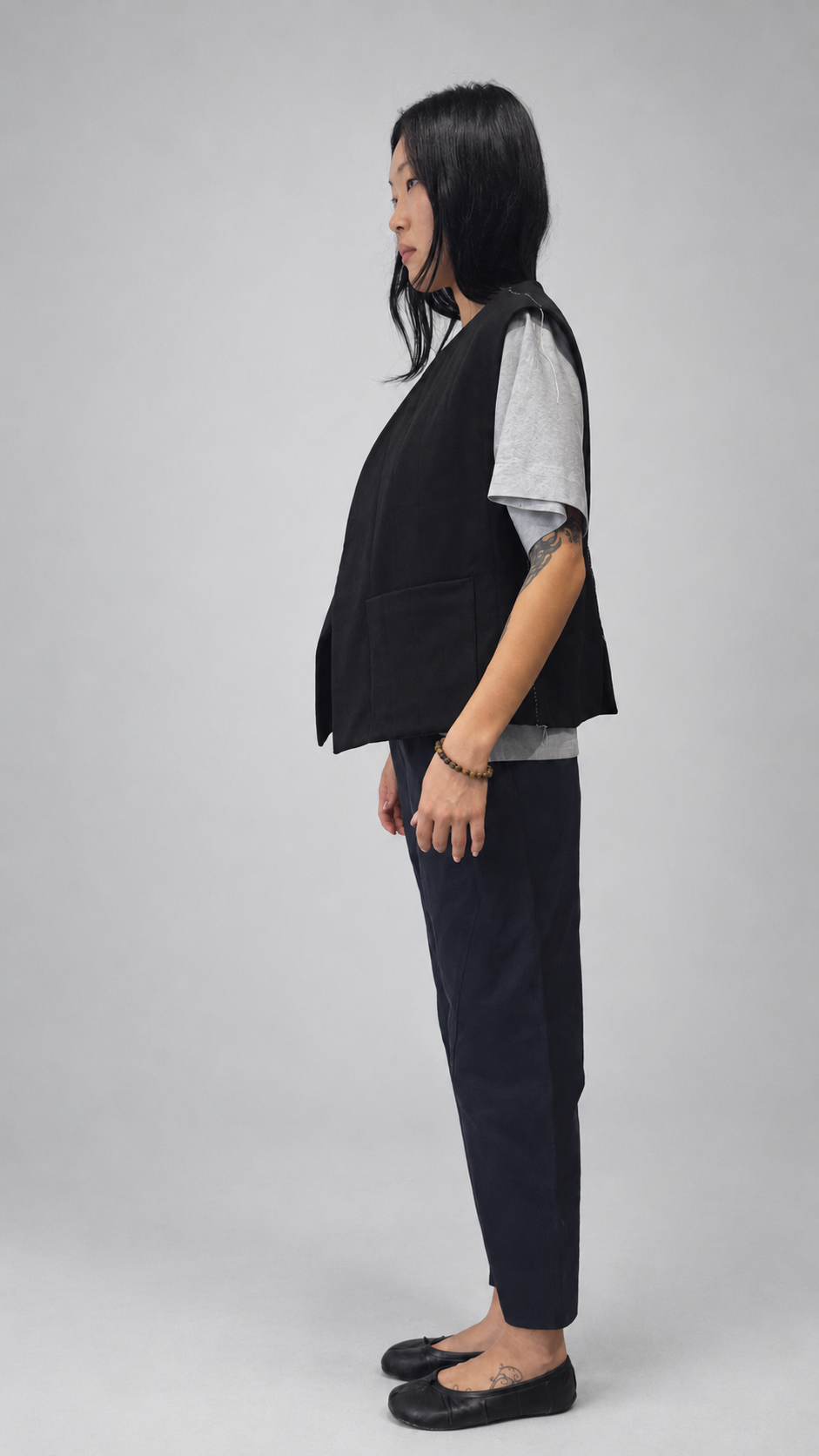 Nubi Vest Classic, Black Wool • Restocked — angled model view. Anujin wearing nubi vest classic black wool, lotus shirt temple grey, twist pants berge.