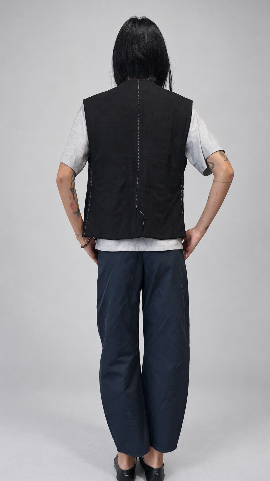 Nubi Vest Classic, Black Wool • Restocked — back model view. Anujin wearing nubi vest classic black wool, lotus shirt temple grey, twist pants berge.