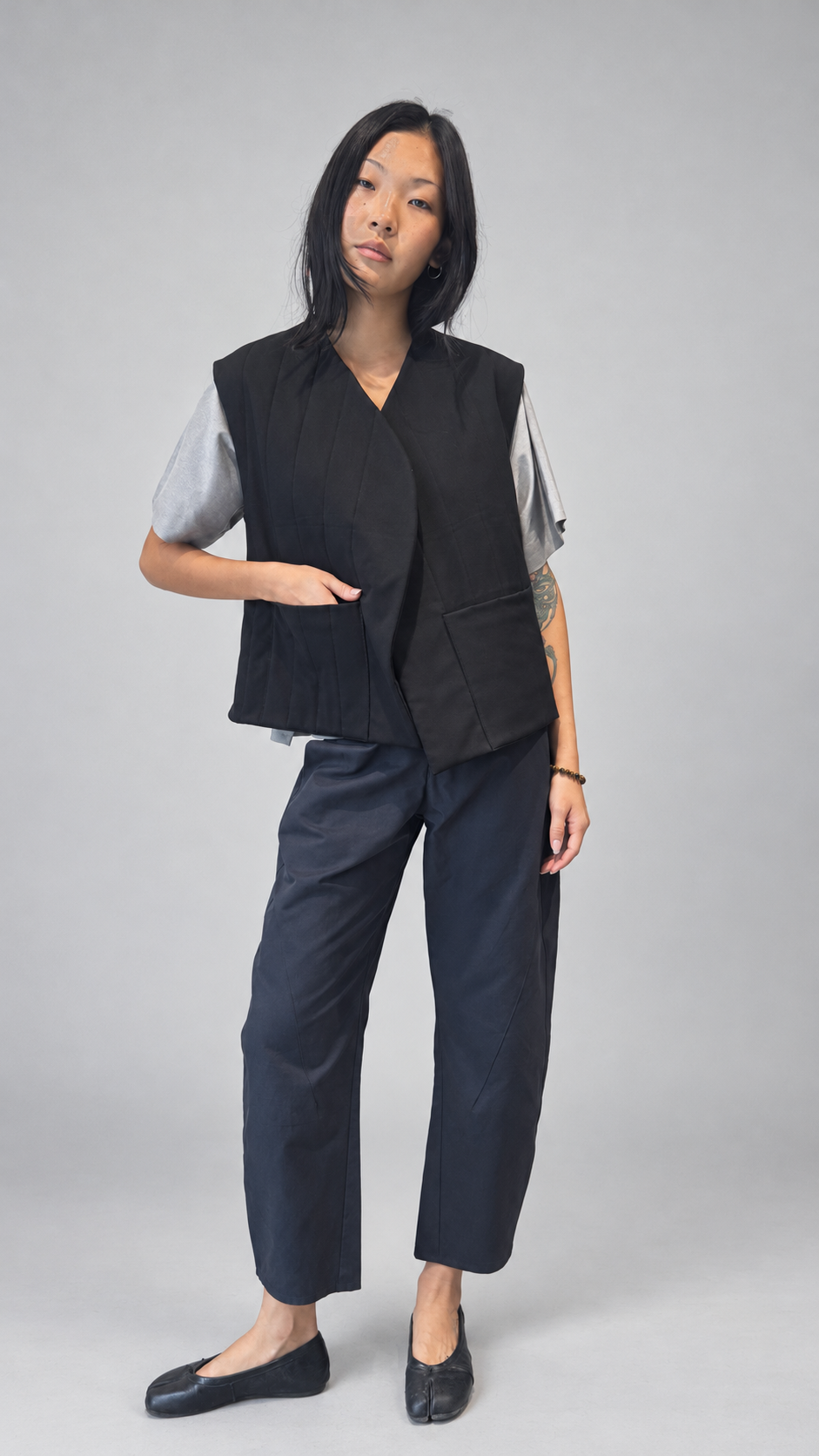 Nubi Vest Classic, Black Wool • Restocked — detail or alternate model view. Anujin wearing nubi vest classic black wool, lotus shirt temple grey, twist pants berge.