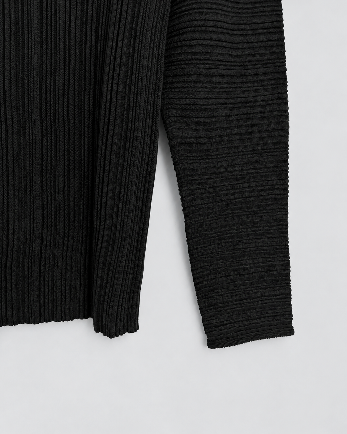 NINA YUUN Wool-Cotton Pleated Pullover in black — detail of horizontal sleeve pleats beside the vertically pleated body and hem.